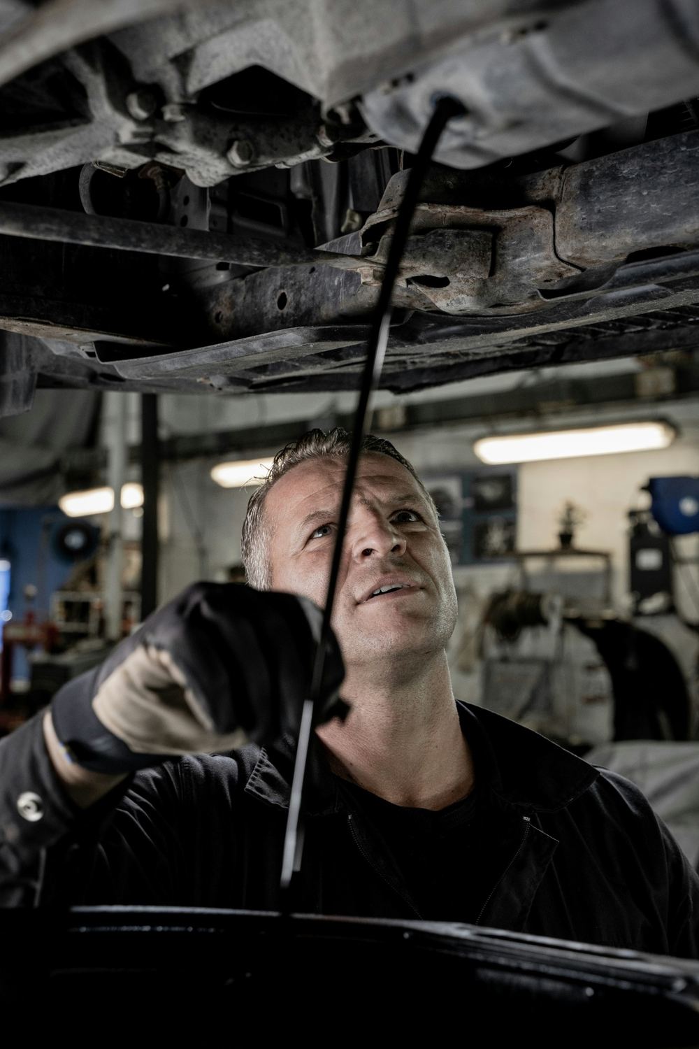 Technician working under a car on a lift in the service bay